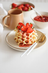Belgian waffles with strawberries and fresh jam on white table. Summer food concept. Soft focus