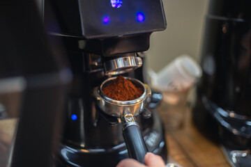 Barista grind coffee bean with grinder machine. The barista prepares coffee.