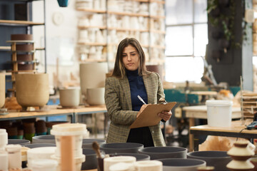 Ceramics studio owner taking inventory in a pottery workshop