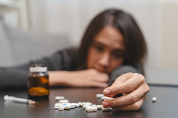 Anti drug, drug addict asian young woman, girl hand reaching for syringe, medicament with narcotic on table at home, abuse overdose. Sick pain of health, unhealthy people. Suicide depressed or despair