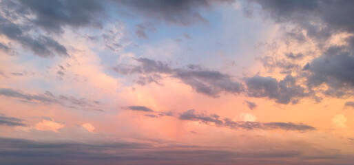 Obraz premium A beautiful pastel-colored evening sky with soft clouds illuminated by the warm light of the setting sun, creating a tranquil and serene atmosphere.