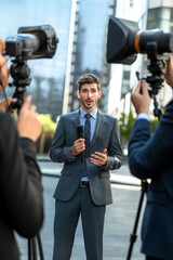 Male news anchor, journalist with a microphone broadcasts live news from the scene.