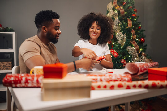 Holiday spirit thrives as a diverse couple wraps Christmas presents.