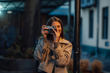 Young female photographer taking pictures outdoors with vintage camera
