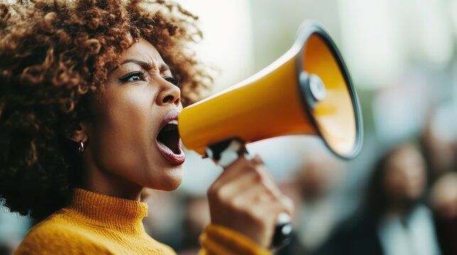 An expressive woman uses a bright yellow megaphone to project her voice in a dynamic and persuasive manner, embodying energy and a quest for change in public spaces.