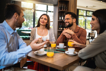 Group of friends chilling at the cafe. Talking, drinking coffee and orange juice.