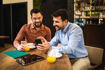 Two colleagues hanging out at the coffee shop. Working together on tablet.