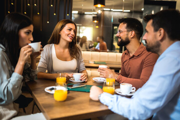 Group of friends met at the cafe. Drinking coffee and orange juice. Girl and guy are talking while the other friends are listening to them.