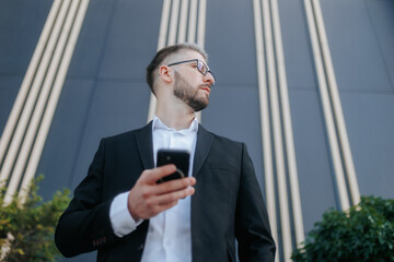 Portrait of a Professional Man in a Suit with a Smartphone, Set Against a Dark Wall