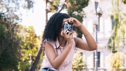 Woman using digital camera while photographing in city park