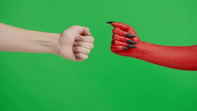 Creepy halloween devil monster hand in red paint with black nails fist bumps with female, isolated on chroma key green screen background, workspace mockup.