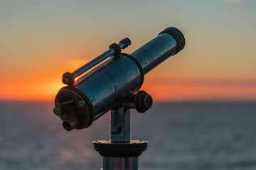 Binoculars at the pier in Scheveningen during sunset. Red glowing sky, warm light, tranquil scene. The Hague, Netherlnds.