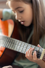 Fototapeta premium A cute girl plays the guitar. A little girl with a guitar.