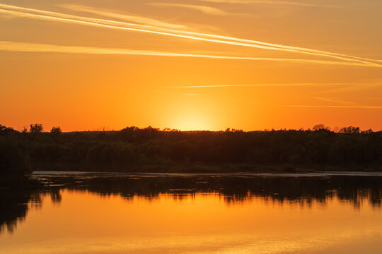 beautiful golden sunset reflecting in the water with contrails in the sky