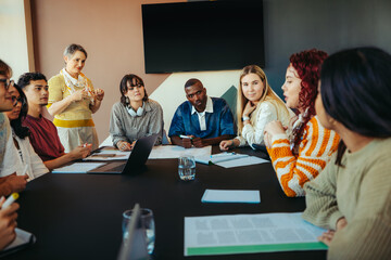 Group of diverse classmates engaged in a collaborative learning discussion around a table in a...