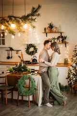 a couple in love hug each other against the backdrop of lights in the kitchen of their home. Christmas family holiday