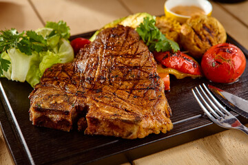 Grilled T-Bone Steak with Roasted Vegetables on Wooden Plate - Close-Up Food Photography
