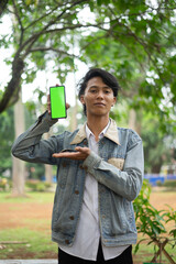 Southeast Asian man showing something on his smartphone with a green screen, perfect for customizable content