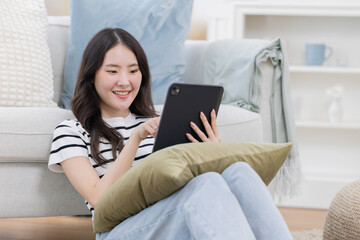 Asian woman watch tablet near a sofa in the living room