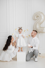 Caucasian family celebrating young girl's second birthday. Parents with two-year-old daughter in...