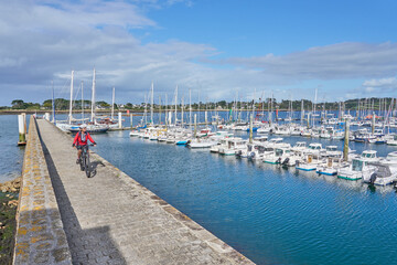 Obraz premium nice senior woman cycling with her electric mountain bike Aber Wrach harbour in Brittany, France 