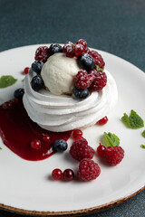 Pavlova with berries and whipped cream on a white plate