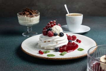 Pavlova with berries and whipped cream on a white plate