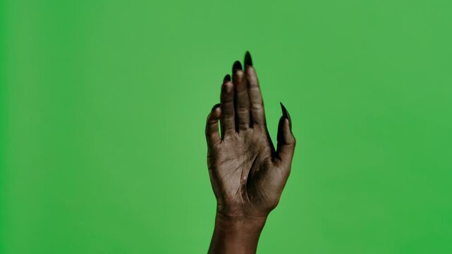 Creepy halloween devil monster hand in black paint with nails shows open palm, isolated on chroma key green screen background, workspace mockup.