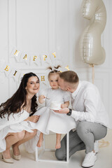 Caucasian mother, father, and young daughter celebrating second birthday. Family joyfully gathered...