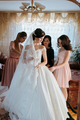 Naklejka premium A woman in a white robe stands next to a wedding dress. She is smiling and she is happy
