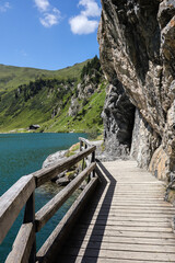 Obraz premium Vertical Landscape of Alpine Lake with Wooden Footpath in Kleinarl. Tappenkarsee in Beautiful Nature in Austria.