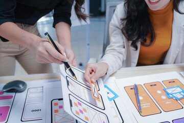 Two female designers collaborate on a mobile app, brainstorming ideas and refining the user...