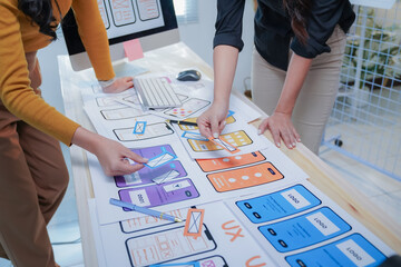 Two female designers are working on a new mobile application, arranging and rearranging the elements of the user interface to improve the user experience