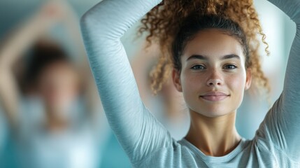 A woman with a bright smile stretches her arms upwards in a group exercise class, embodying enthusiasm, health, and vitality amidst a supportive community setting.