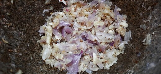 Garlic herbs and red onions in stone mortar with pestle