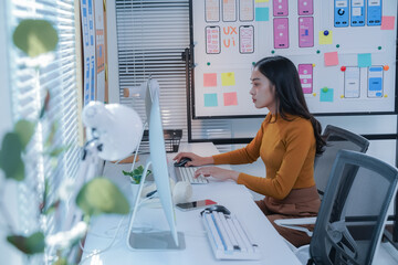 Focused asian woman designs user-friendly apps in a creative. Professional office setting....