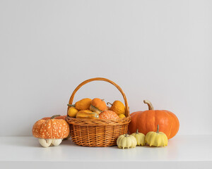 Autumn harvest of pumpkins in basket on white background. Different varieties of pumpkins on the table. Thanksgiving or Halloween time. Copy space.