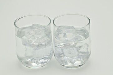 Two glasses of water with ice cubes, close up, isolated on white background