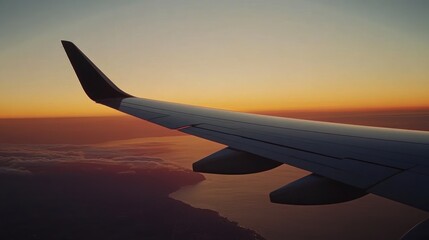 Obraz premium Aerial view of an airplane wing during sunset over the ocean.