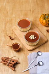 Dessert, creamy pumpkin panna cotta with caramel sauce in glass bowls on wooden background....