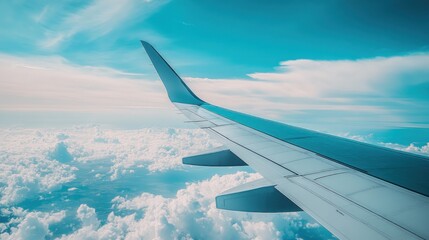 Obraz premium Aerial view from an airplane wing above fluffy clouds under a bright blue sky.