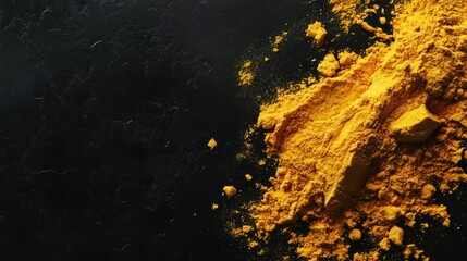 A close-up of yellow turmeric powder on a dark surface, showcasing its vibrant color and texture.