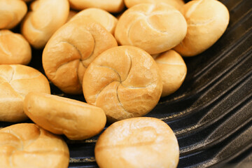 Fresh Kaiser rolls stacked on a store shelf. Group of classic bread rolls on display. Bakery section with a pile of golden brown buns. Perfect for sandwiches or breakfast. Crisp, freshly baked roll.