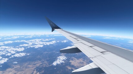 Obraz premium Aerial view from an airplane wing over clouds and landscape.