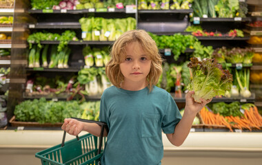Child with lettuce salad. Shopping with kids. Kid buying fruit in supermarket. Little boy buy fresh vegetables in grocery store. Kid choosing vegetables. Healthy food.
