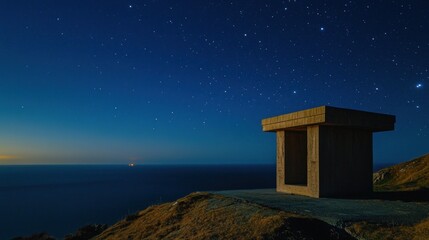 Fototapeta premium A solitary structure overlooks the ocean under a starry night sky.