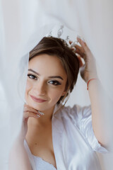 Fototapeta premium A woman is wearing a white robe and a tiara. She is smiling and looking at the camera