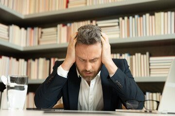 Business man suffering from headache after computer work, exhausted with closed eyes touching head, relieving pain, migraine. Business problems. Bankruptcy, financial problem and crisis concept.