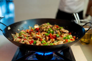The chef cooks shrimps with vegetables in a wok.