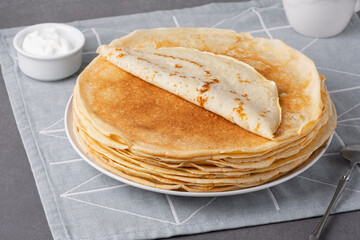 Pancakes with sour cream on a grey table